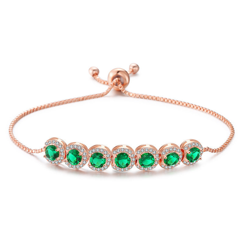 Rose gold bracelet with green gemstones on a white background