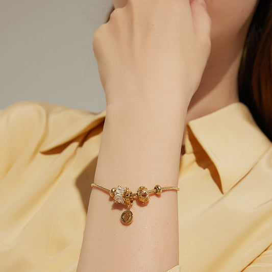 Gold bracelet with charms on a wrist against a neutral background