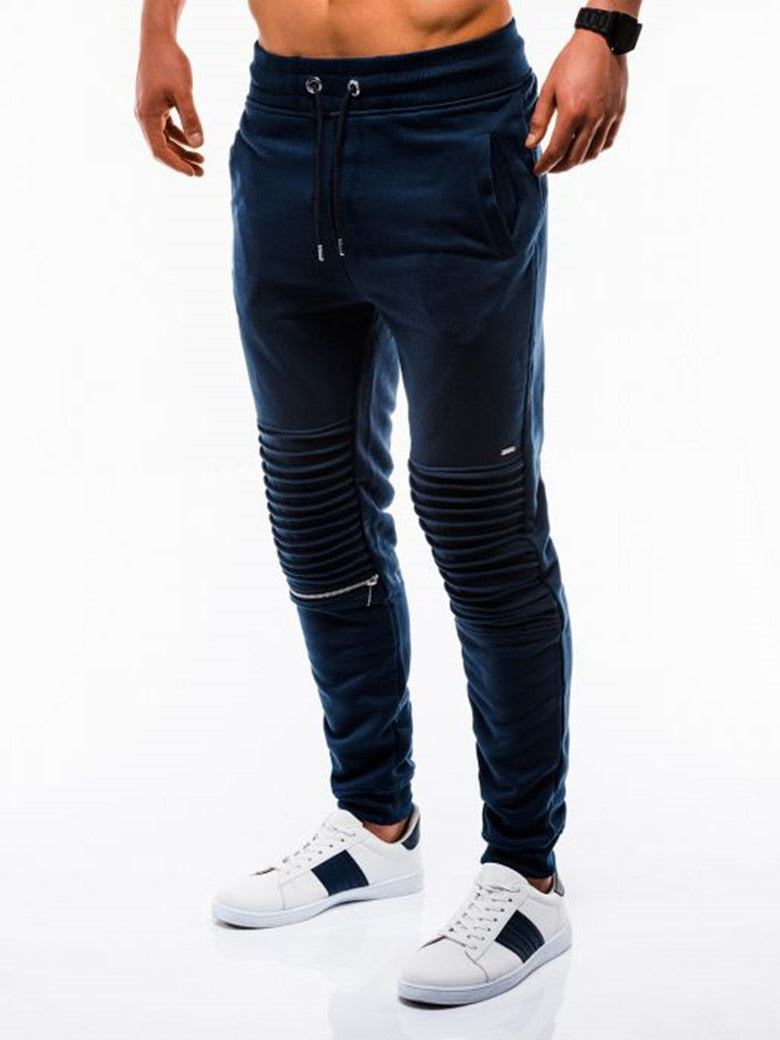 Navy blue jogger pants with zippers on a white background