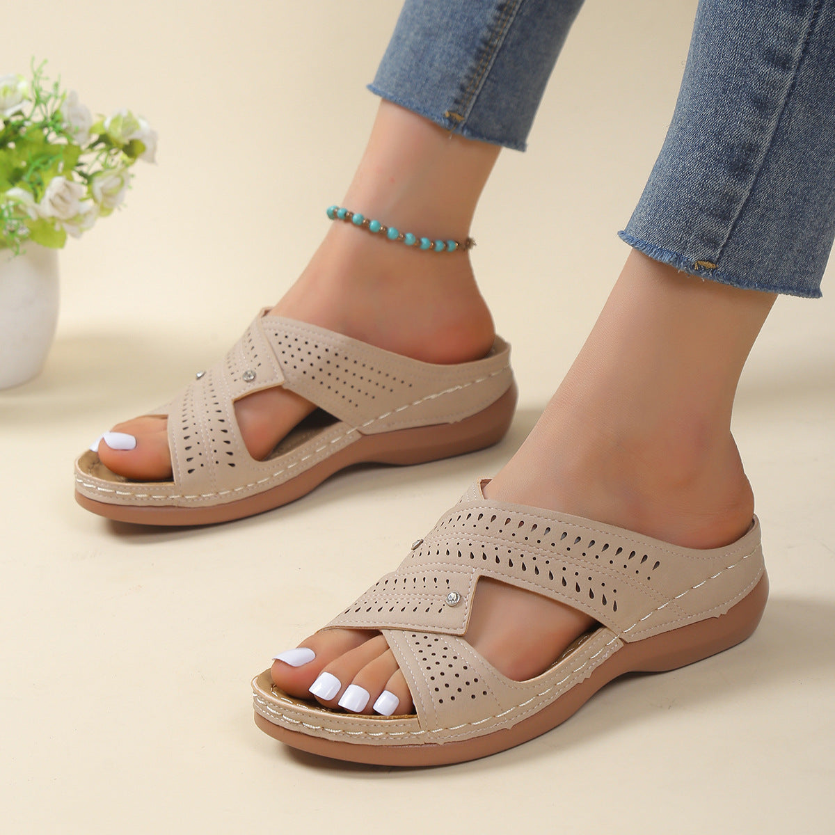 Beige sandals worn with rolled-up jeans on a light background