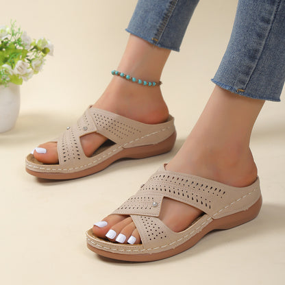 Beige sandals worn with rolled-up jeans on a light background