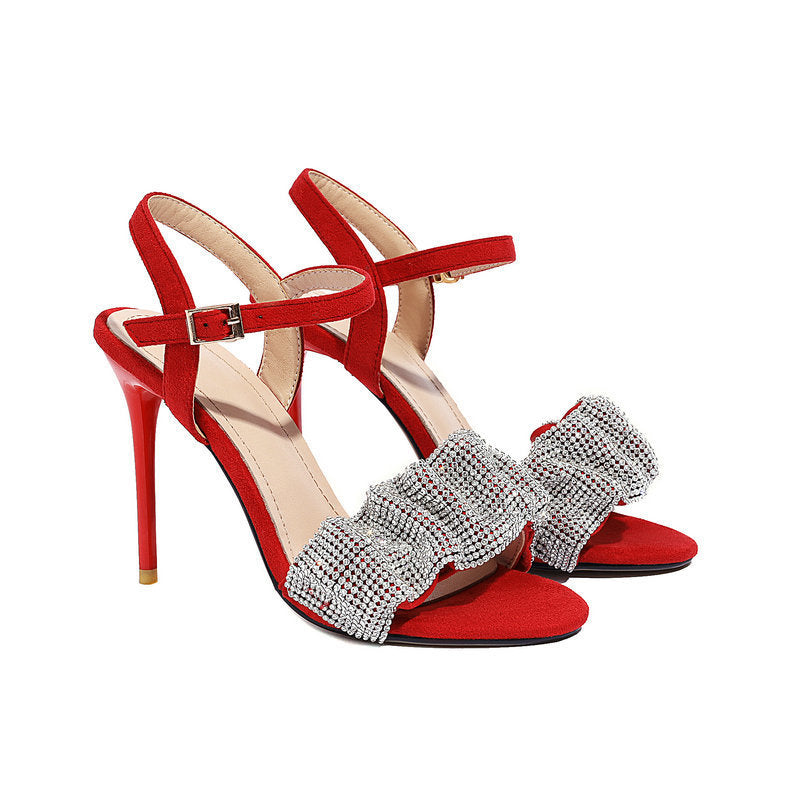 Red high-heeled sandals with silver bow embellishments on a white background