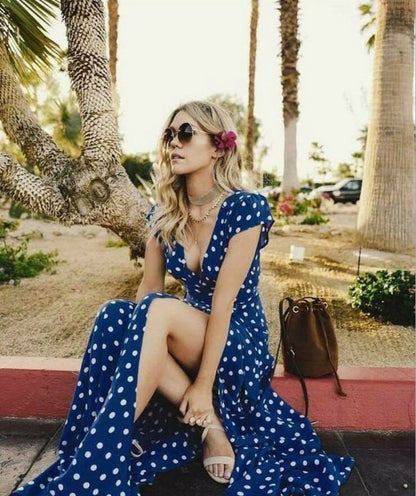 Woman in a blue polka dot dress sitting under palm trees