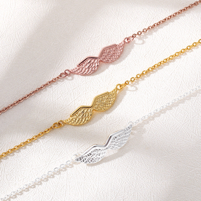 Three gold chain bracelets with wing designs on a white background