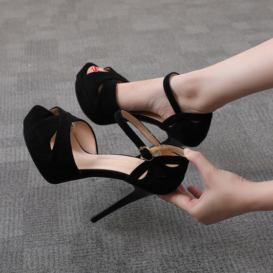 Black high-heeled shoes with cut-out design on a gray carpet