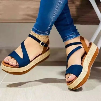 Blue sandals with brown soles worn by a person in blue jeans on a neutral background