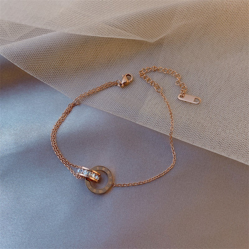 Rose gold bracelet with a circular charm on a soft fabric background