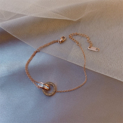 Rose gold bracelet with a circular charm on a soft fabric background