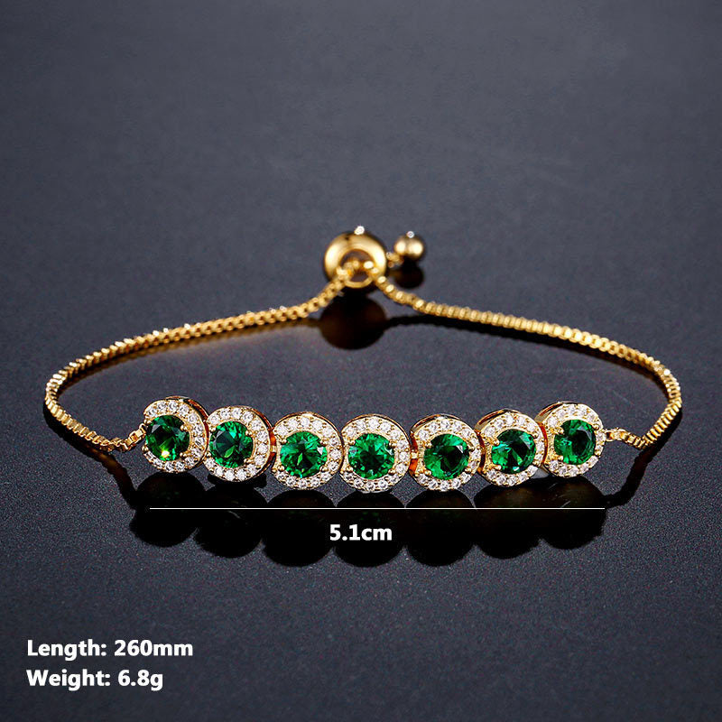 Gold bracelet with green gemstones on a dark background