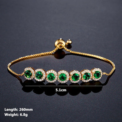 Gold bracelet with green gemstones on a dark background
