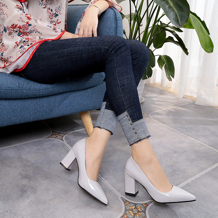 Person wearing white high-heeled shoes sitting on a blue chair with a plant in the background.