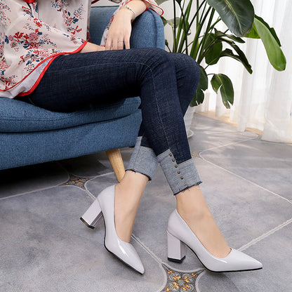 Person wearing white high-heeled shoes sitting on a blue chair with a plant in the background.