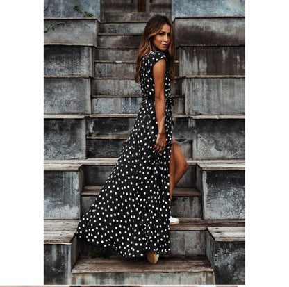 Woman in a black and white polka dot dress standing on a set of concrete stairs.