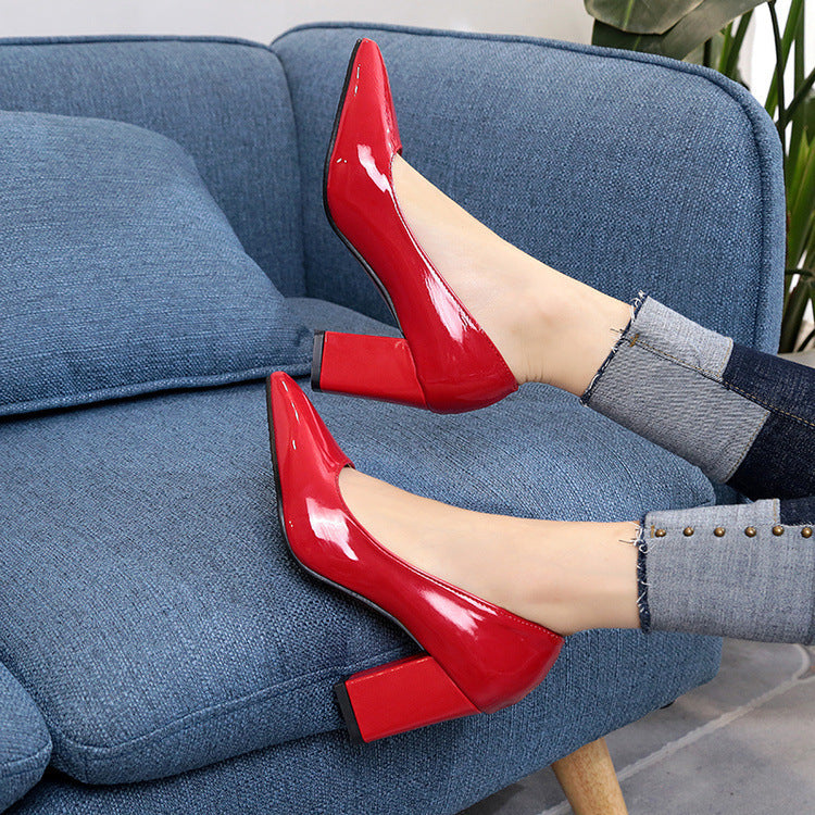 Red high-heeled shoes worn by a person sitting on a blue couch.