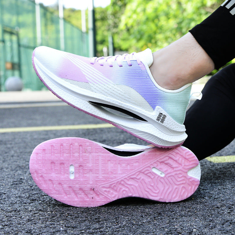 White and pink running shoes on a black surface with greenery in the background