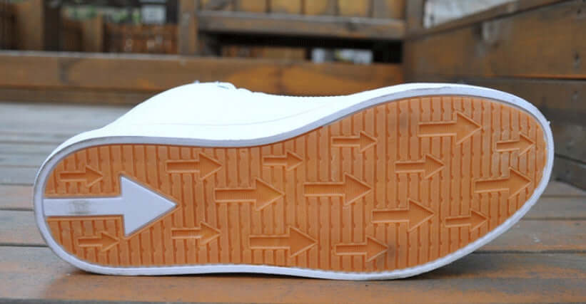 Close-up of a white sneaker with a brown sole on a wooden surface
