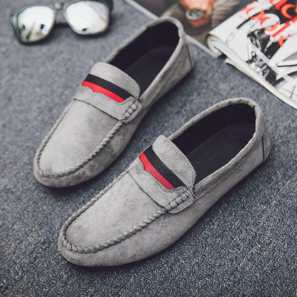 Gray loafers with red and black accents on a textured surface