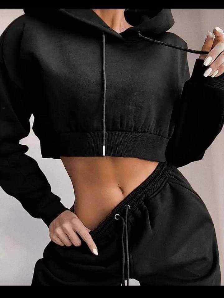 Person wearing a black cropped hoodie and matching pants against a neutral background