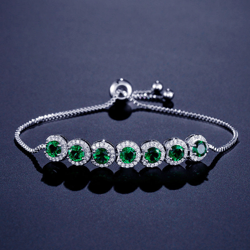 Silver bracelet with green gemstones on a dark background