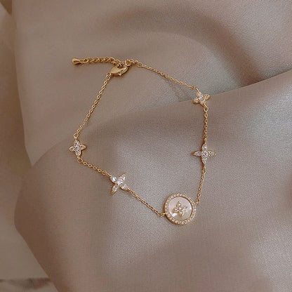 Gold bracelet with floral and circular designs on a beige fabric background