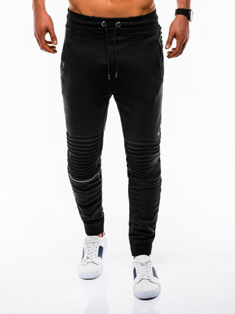 Black jogger pants worn by a person on a white background