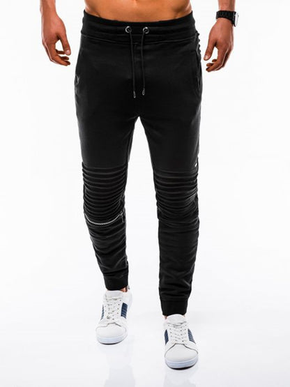 Black jogger pants worn by a person on a white background