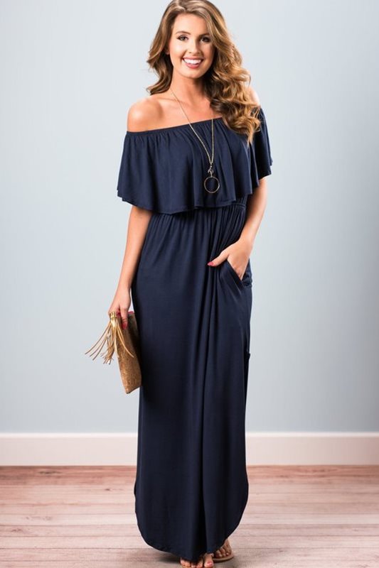 Woman wearing a navy off-shoulder dress against a plain background