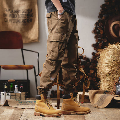 Person wearing brown cargo pants and yellow boots in a rustic setting with hay and wooden elements.