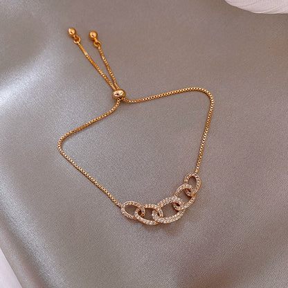 Gold chain bracelet on a soft gray background