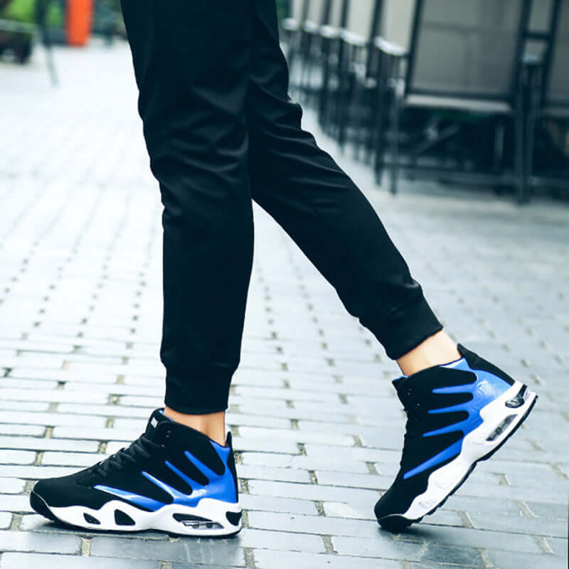 Person wearing black and blue athletic shoes on a blurred outdoor background