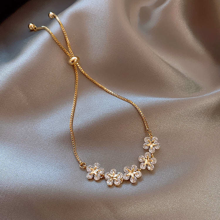 Gold bracelet with floral designs on a soft fabric background