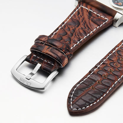 Brown leather watch strap with silver buckle on a white background