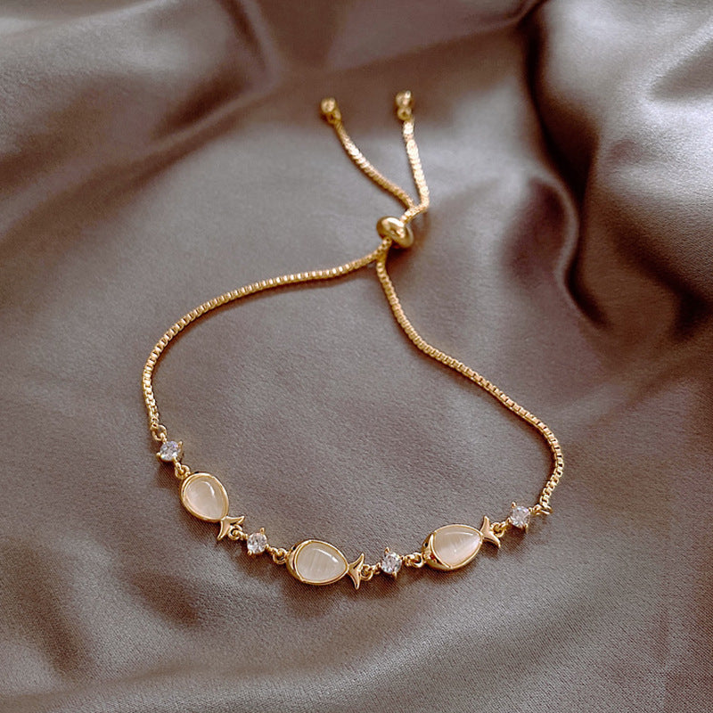 Gold bracelet with gemstones on a soft fabric background