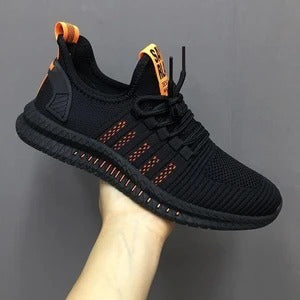 Black running shoe with orange accents on a gray background