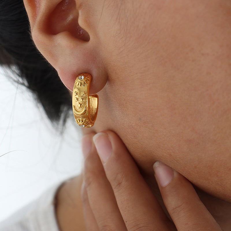 Gold hoop earring worn by a person with a blurred background