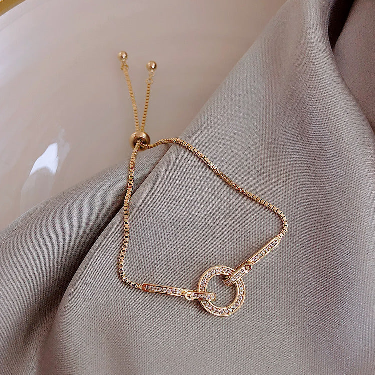 Gold bracelet with interlocking rings on a soft fabric background