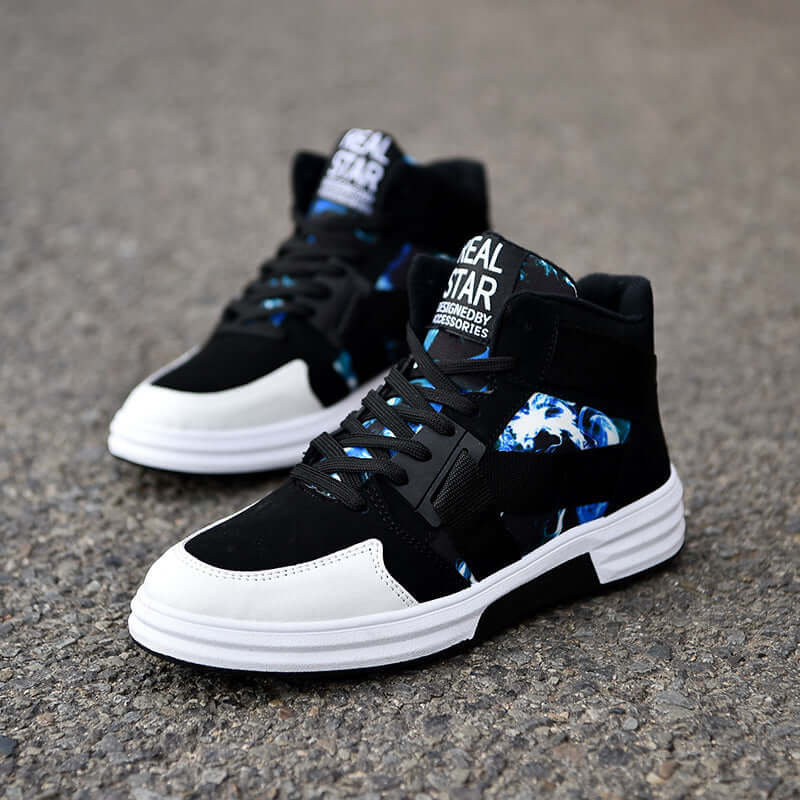 Black and white high-top sneakers with blue accents on a gray pavement background