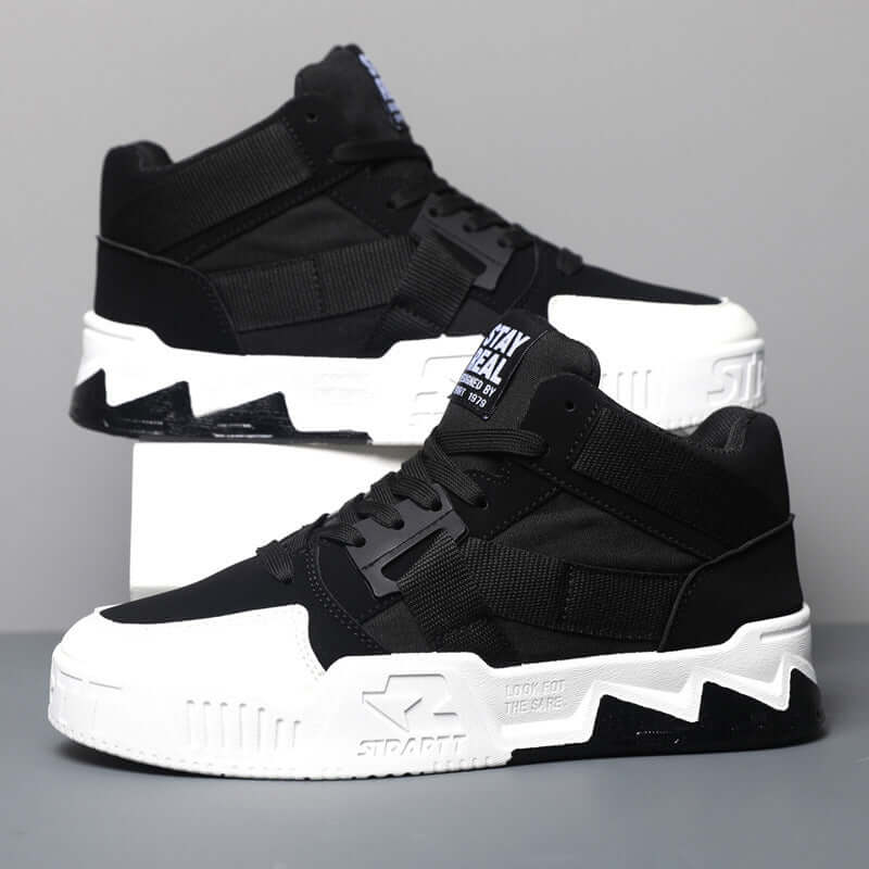 Black and white high-top sneakers with visible branding on a gray background