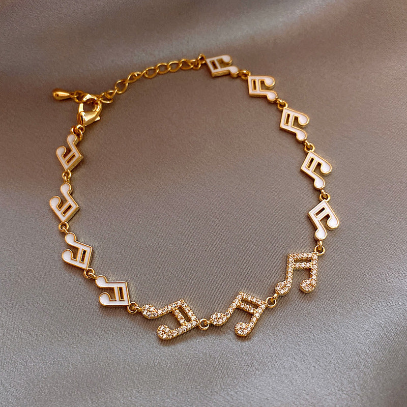 Gold bracelet with musical note charms on a gray background