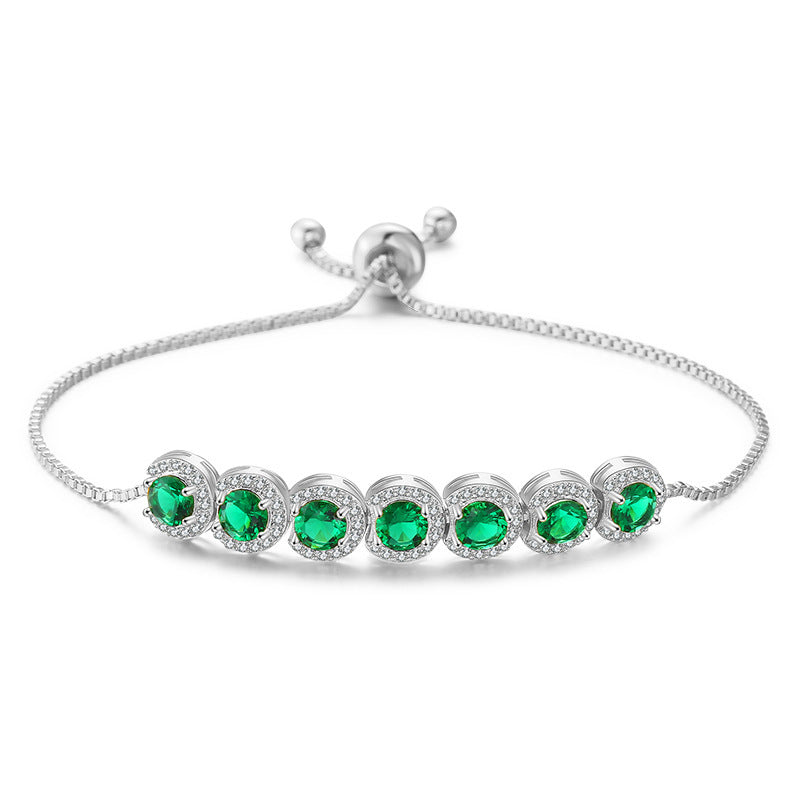 Silver bracelet with green gemstones on a white background