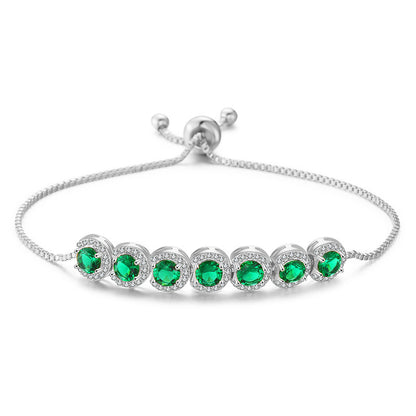 Silver bracelet with green gemstones on a white background