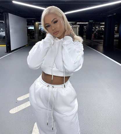 Person wearing a white hoodie and pants in a parking garage
