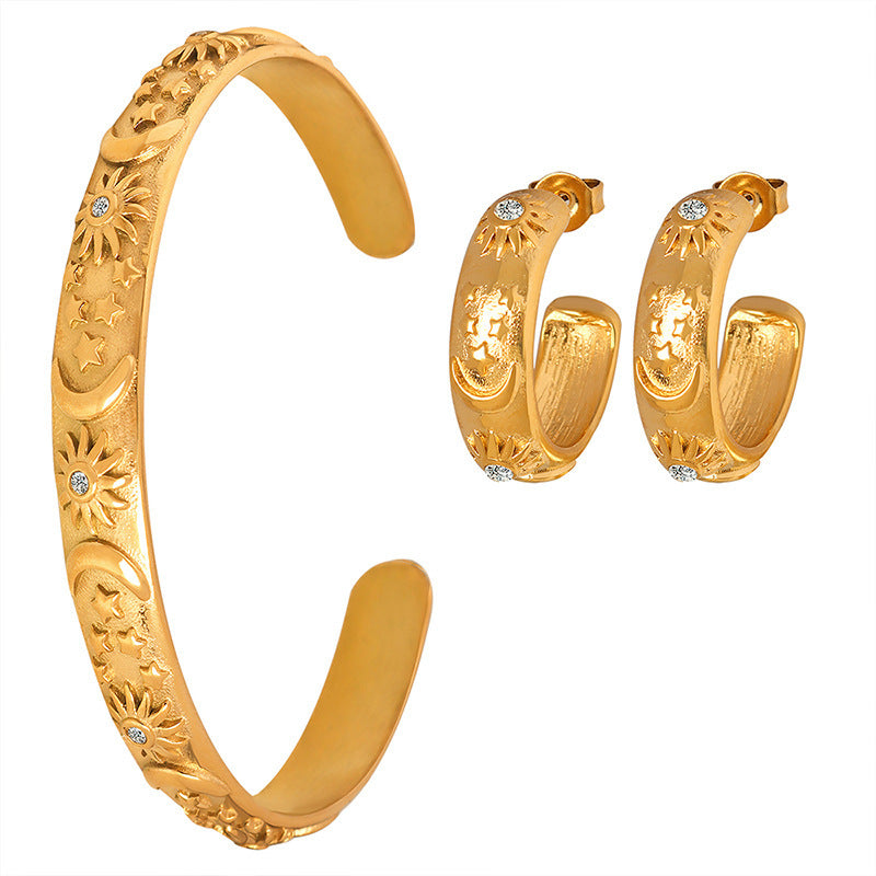 Gold bracelet and hoop earrings on a white background