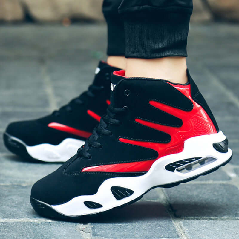 Black and red sneakers with white soles on a blurred pavement background