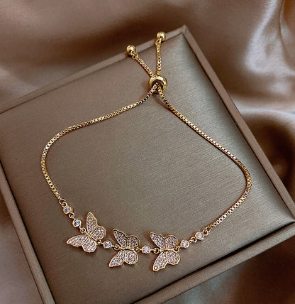 Gold butterfly necklace on a soft brown background