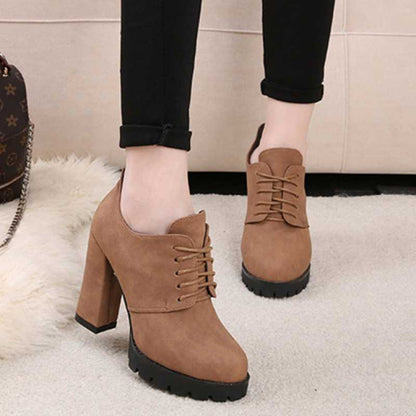 Brown platform shoes worn with black pants on a light background