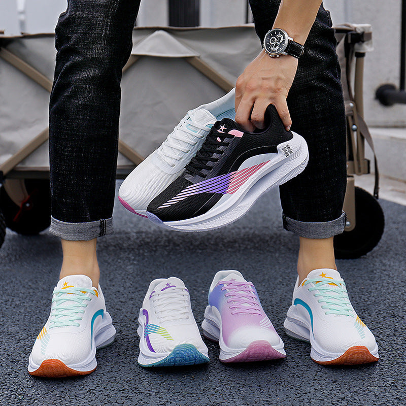 Person holding a black and white sneaker with colorful accents, surrounded by four other sneakers on a dark surface.