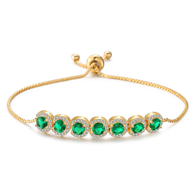 Gold bracelet with green gemstones on a white background