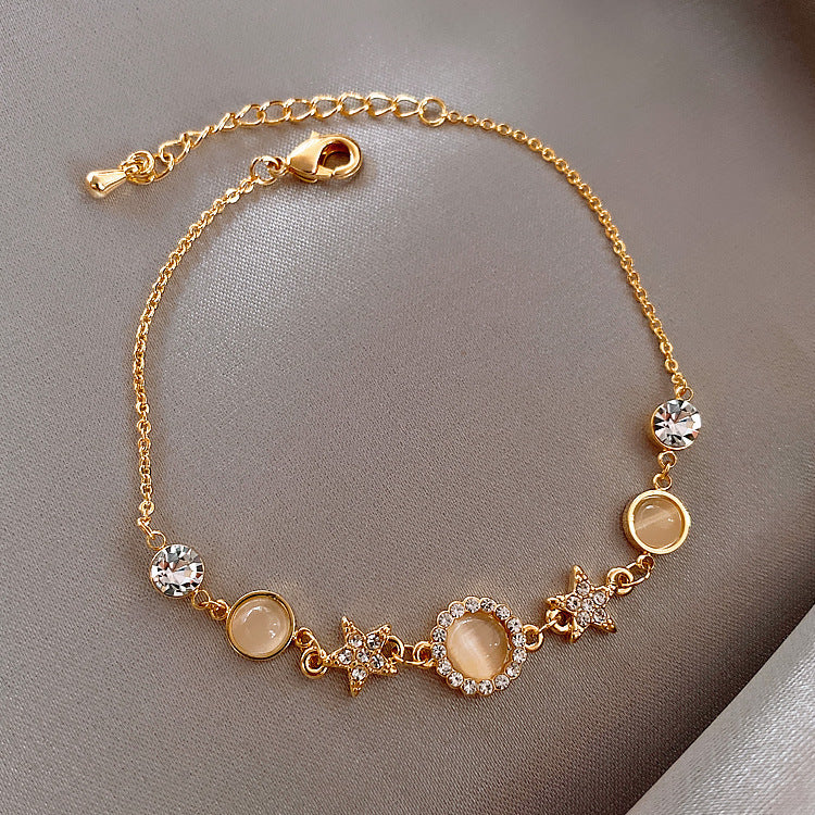 Gold bracelet with gemstones and star charms on a gray background