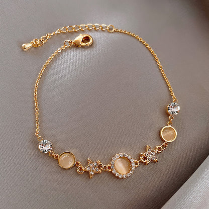 Gold bracelet with gemstones and star charms on a gray background